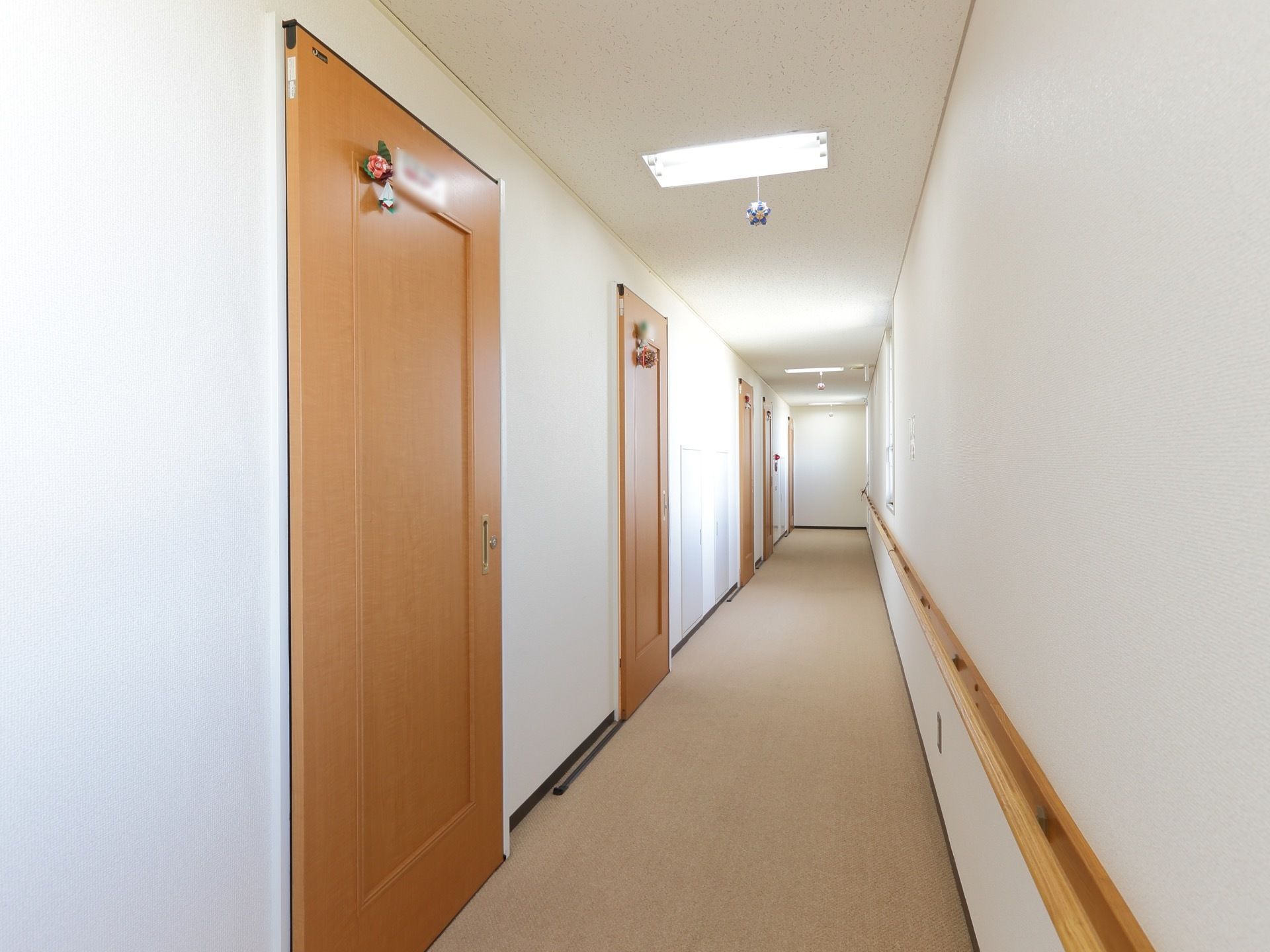 個室が続く長い廊下。各部屋のドアには、飾りとプレートが取り付けられている。ドアは使いやすいよう、引き戸になっている。