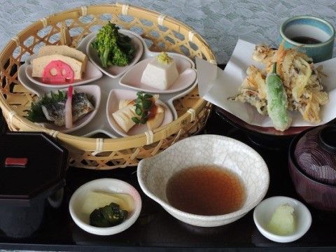 天ぷらに、竹かごに盛られた5つの小鉢や漬物の付いた食事例