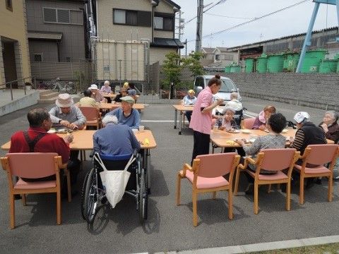 舗装されたスペースにテーブルと椅子を並べて、腰を下ろしている高齢者