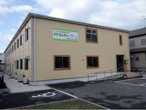 海から近い場所に位置する、２階建ての建物。建物そばに駐車場があるため、容易に出入りできる。入口には階段とスロープがある。