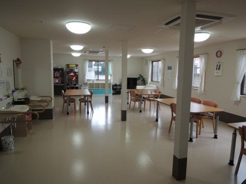 共有のリビングルームは入居者様同士の交流の場として使われており、通路も広く行き来しやすい。テーブルセットが複数設置されている。