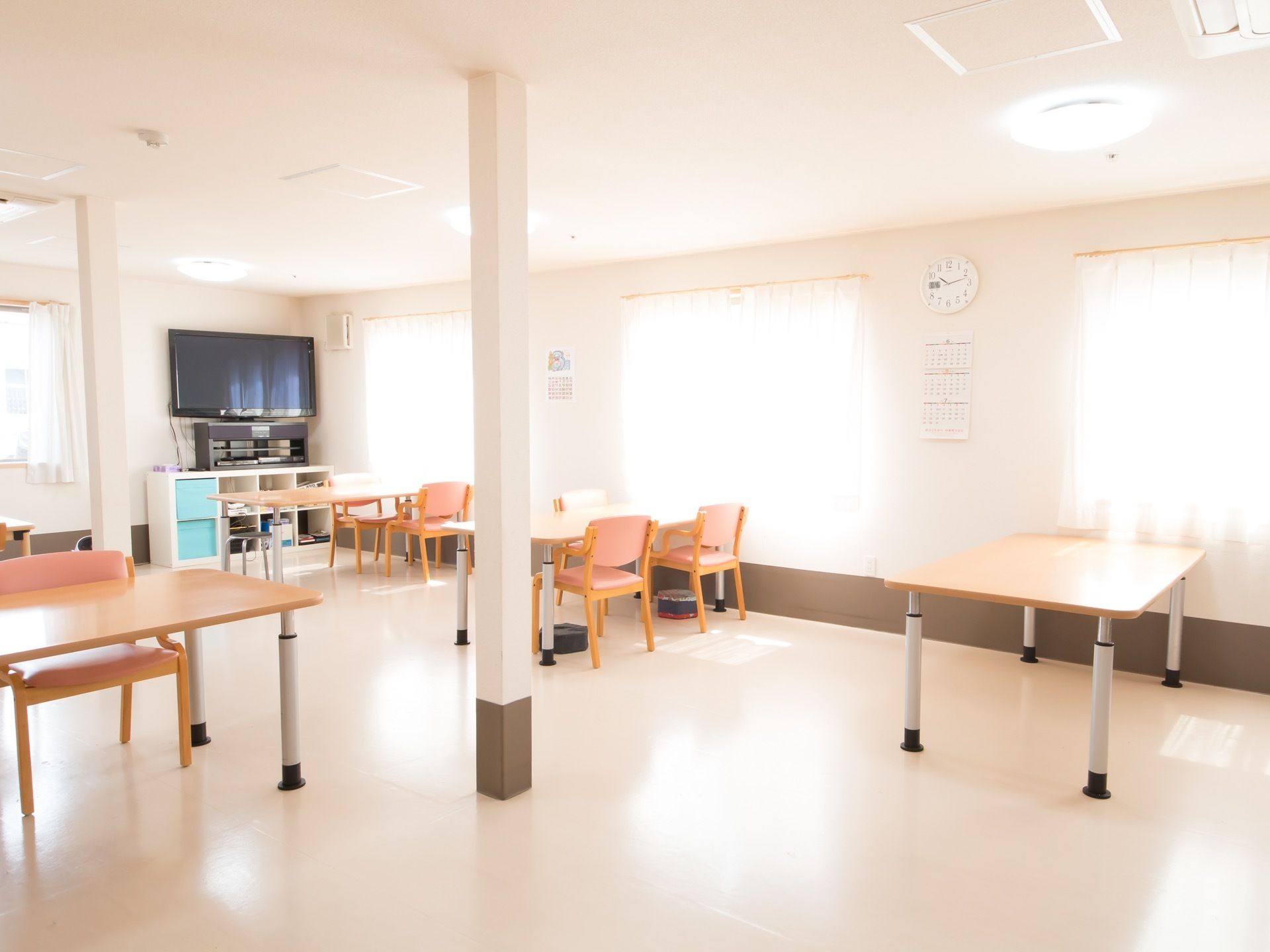 カーテンが掛けられた複数の腰高窓から光が差し込んでいて、食堂内はとても明るい。部屋の中に柱が数本立っている。