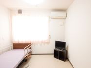 カーテンが掛けられた腰高窓があり、エアコンが設置されている。転落防止柵が取りつけられたベッドが置いてある。