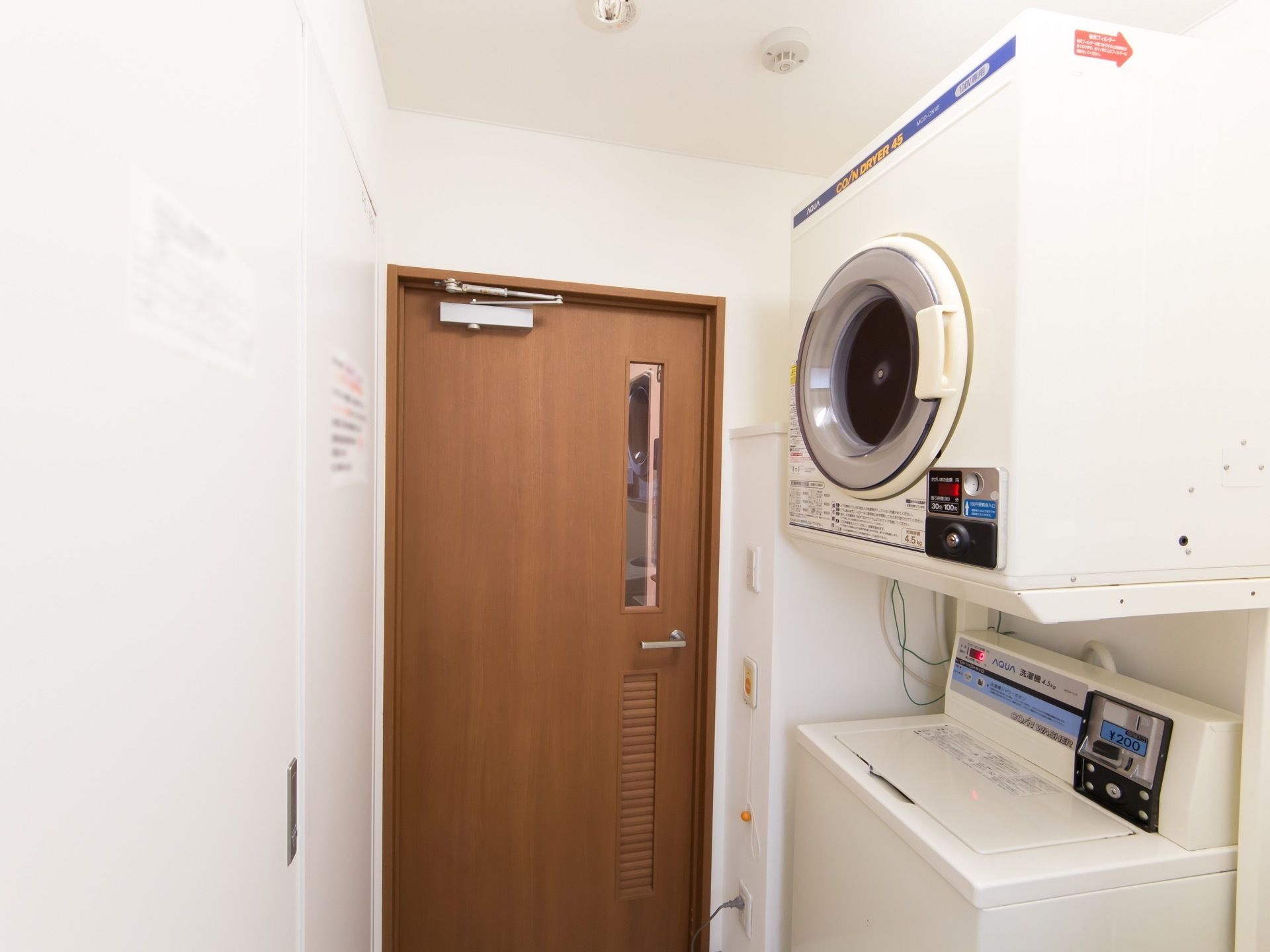 コイン式の洗濯機と乾燥機が置かれた部屋である。さまざまな注意事項が貼られており、自由に使用することができる。
