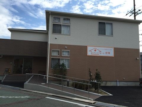 1階はブラウン、2階はベージュに切り替えられた、手前にスロープのある2階建ての建物