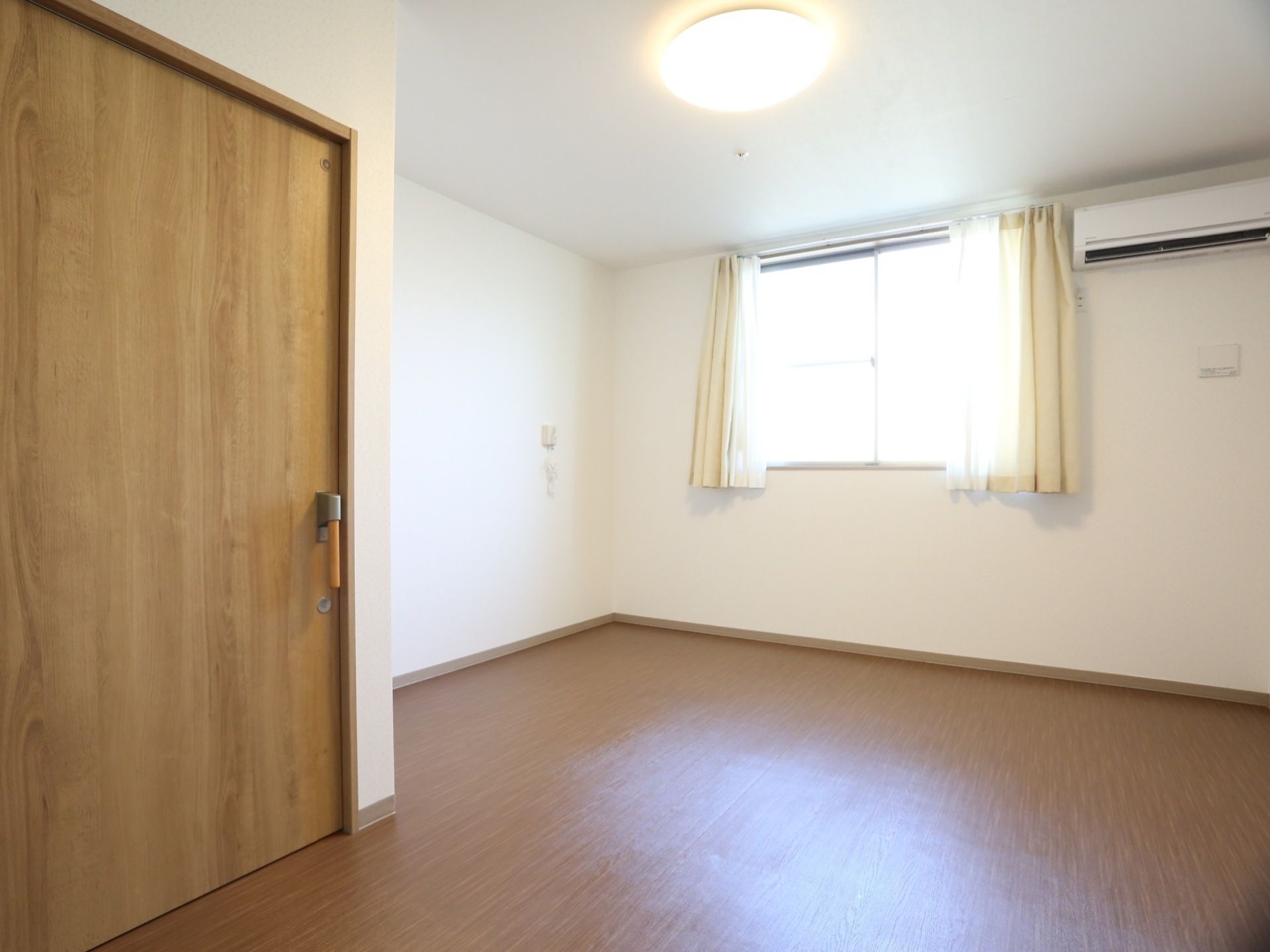 明るく広々としたワンルームタイプの間取りの部屋。木目調の内装が落ち着いていて居心地の良い雰囲気になっている。