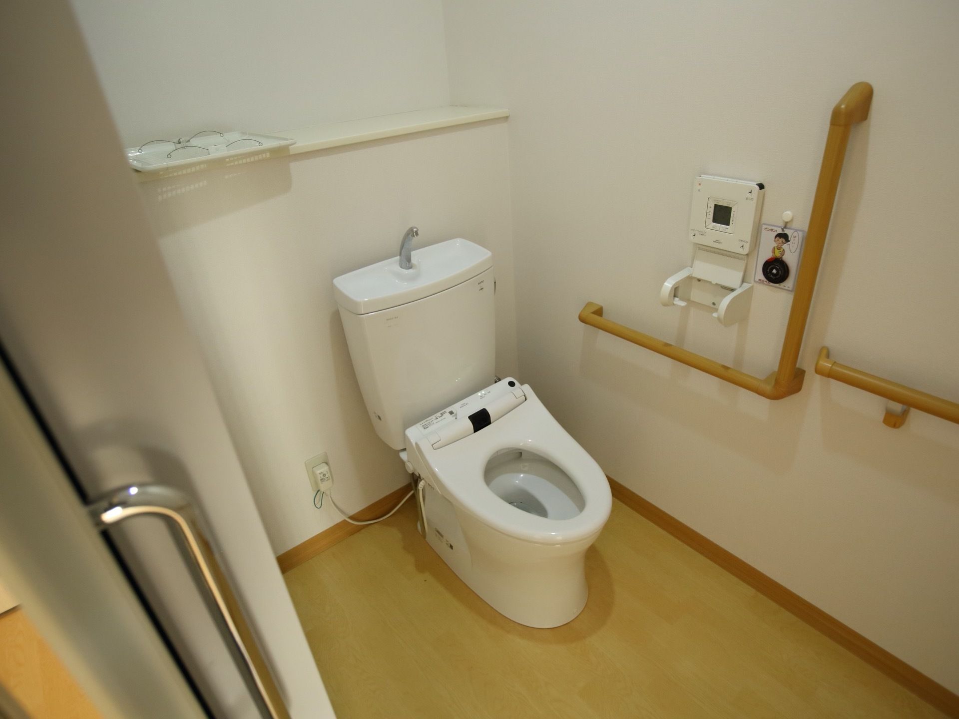 隅々まで清掃のなされた綺麗な洋式トイレである。壁にはL字の手すりをとりつけており、安心して利用することができる。