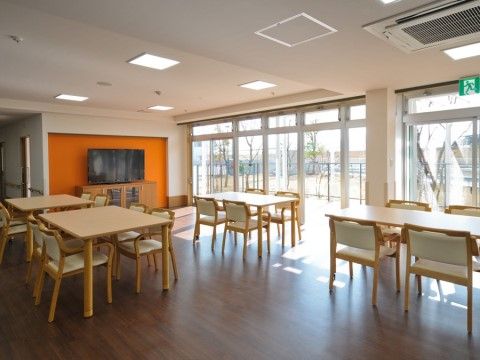 近代的な白いテーブルセットや一面の窓がオシャレで、カフェのような空間になっている。大きなテレビも用意されている。