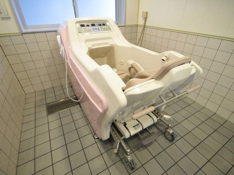 浴室はタイル風の壁や床で覆われており、清潔に保たれている。中央の介護浴槽を通じて、入居者様は座ったままの状態で入浴をすることができる。