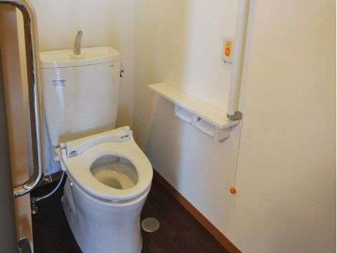 トイレにはスライド式の扉を通じて入室でき、便器は白くきれいに磨かれている。室内の壁にはつかまり用の棒が取り付けられている。