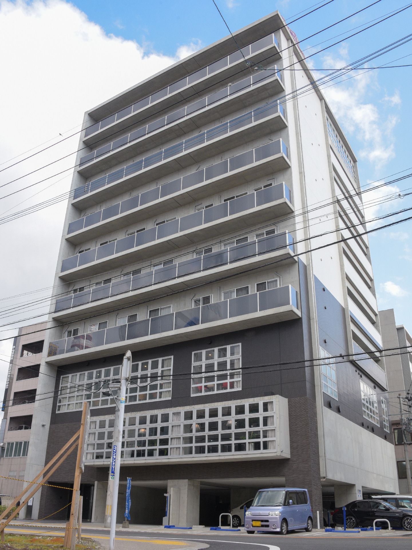 1階はピロティになっていて、2、3階に格子状の窓がある、10階建ての建物