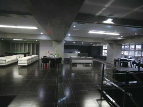 光沢のあるグレーの床の左奥に白いソファが置かれているスペース