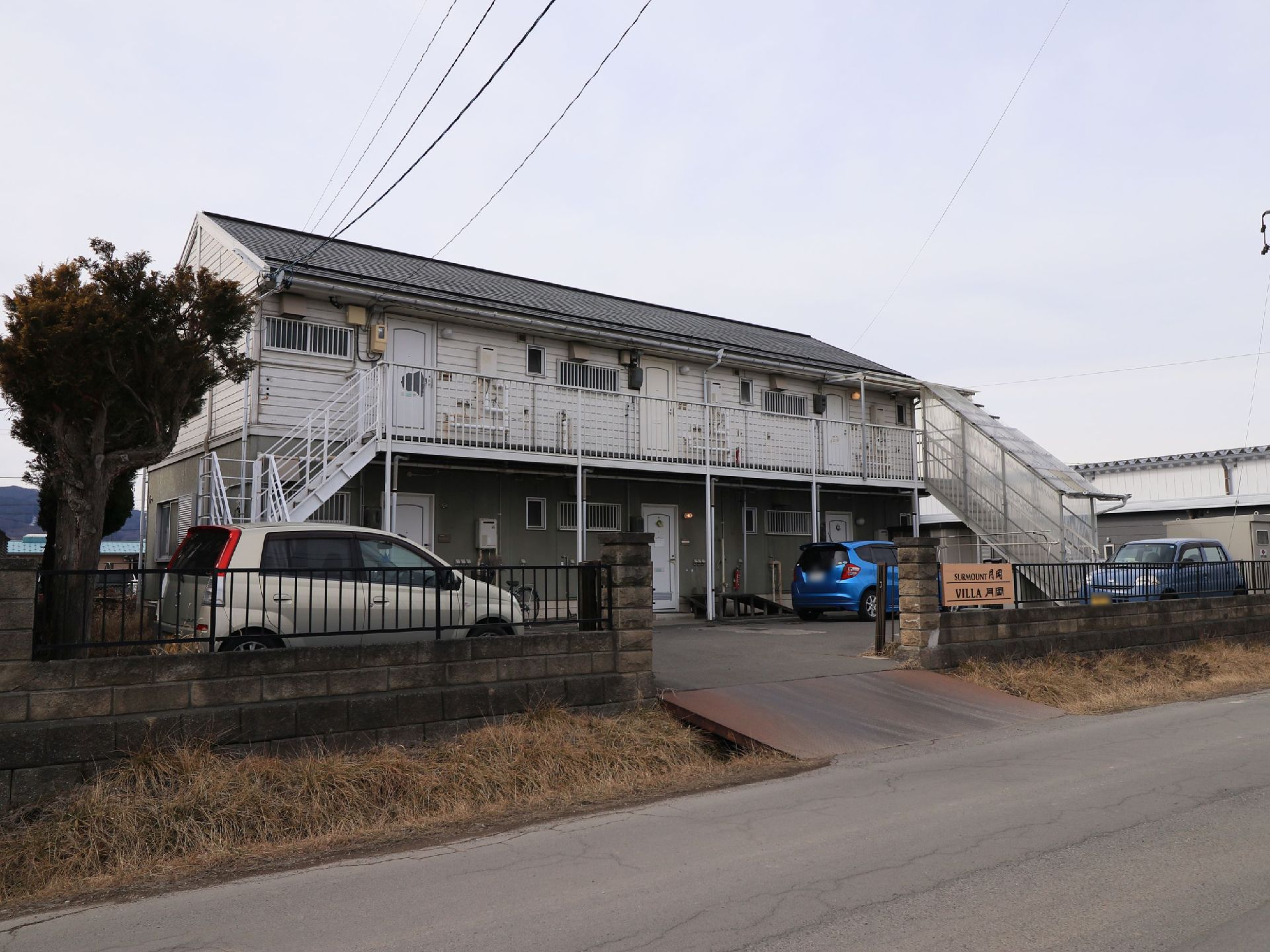 木造２階建ての白い建物である。公道から側溝を挟んだところに位置しており、建物の前に駐車場が設けてある。建物の左右に外階段が設置されている。