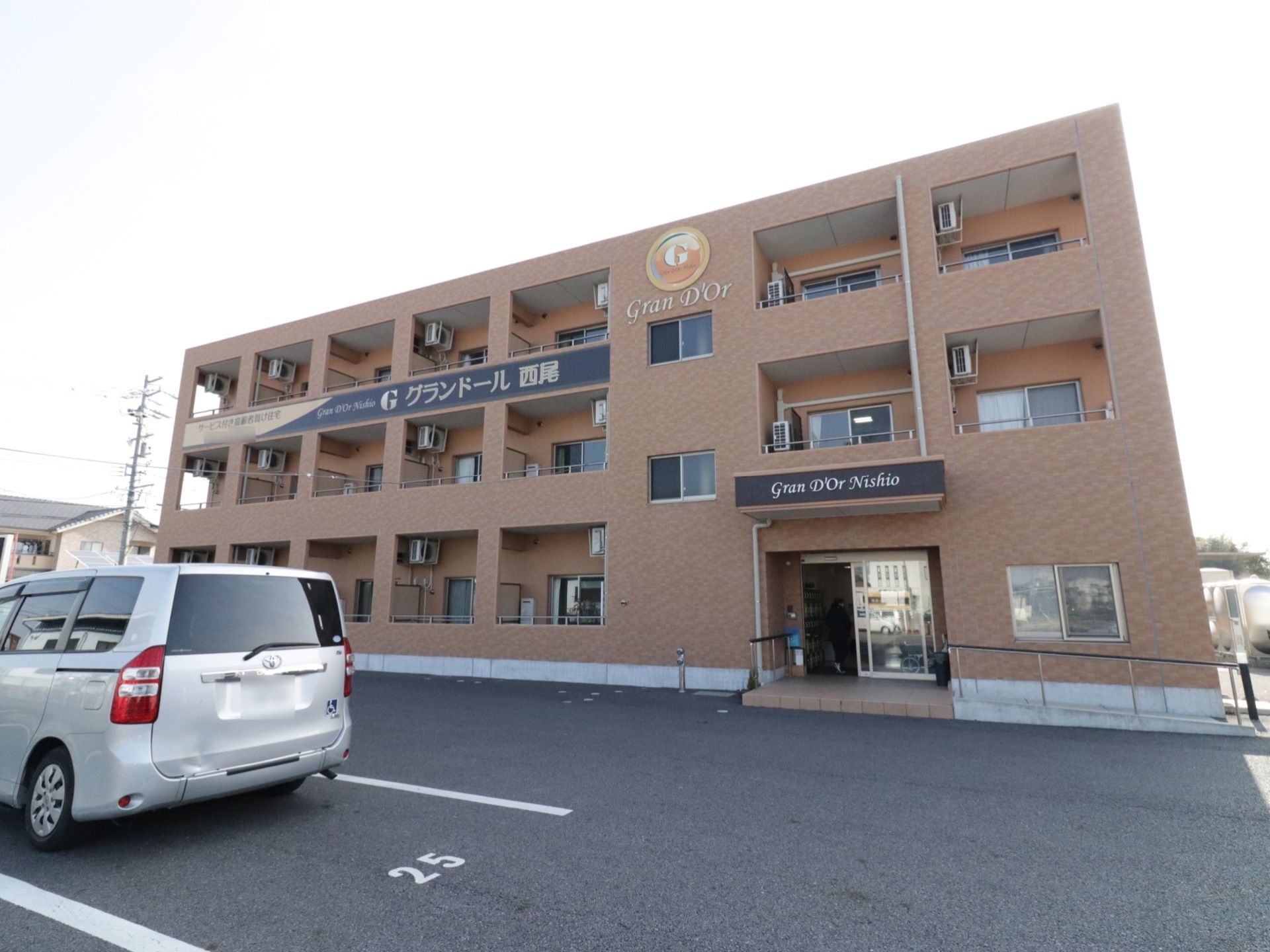 ブラウンのレンガ調の外壁が落ち着いた雰囲気の外観。敷地内には駐車スペースが完備されている。玄関前には手すり付きのアプローチが設置されている。