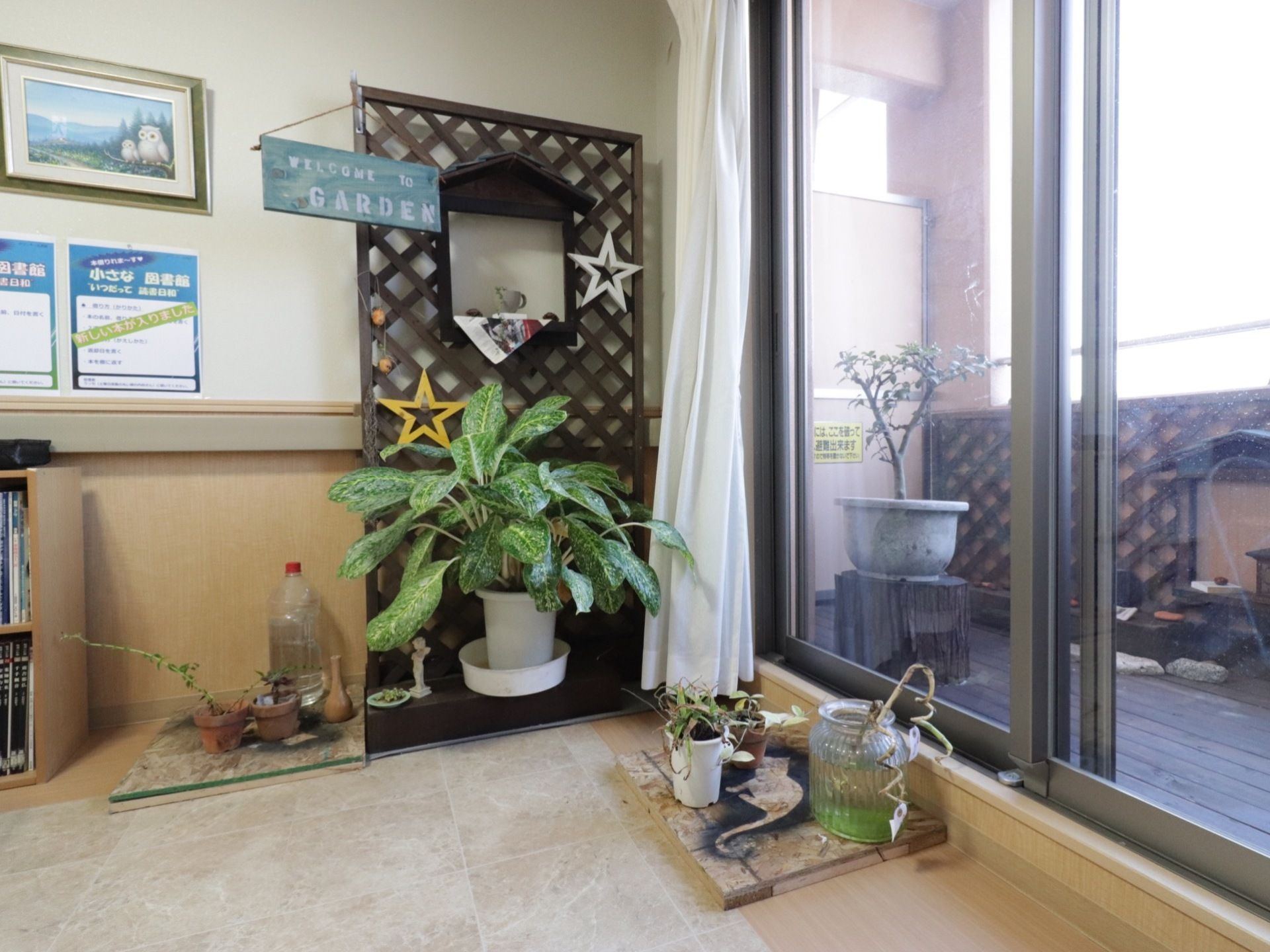 木製のデッキタイプのガーデン。室内から出入りできるようになっている。観葉植物や可愛らしい植木鉢が置かれている。