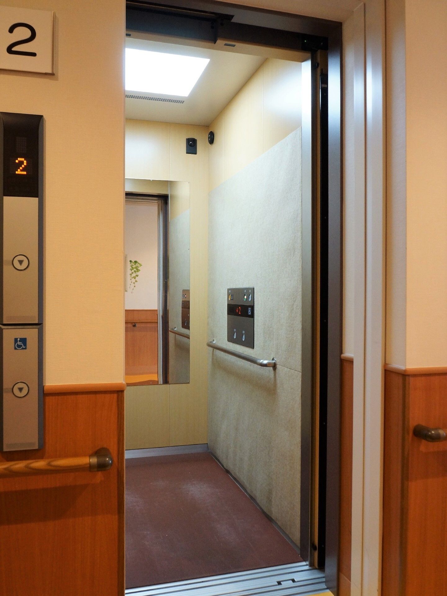 白い壁が明るい階段がある。木の手すりが両側の壁に取り付けられているので、上ったり下りたりするのに配慮してある。