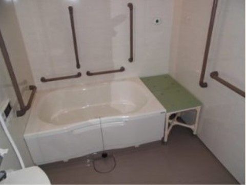 浴槽の横にはバスボードの代わりをする台が置かれ、壁には大きな手すりがある。白っぽい壁に茶色の手すりであり、とても分かりやすい。