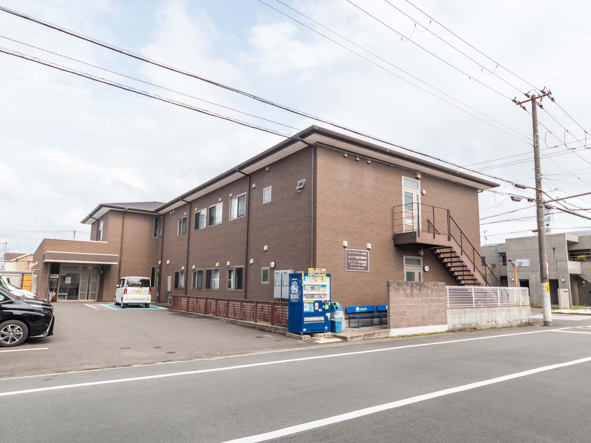 落ち着いたブラウンを基調とした施設外観と施設の駐車場