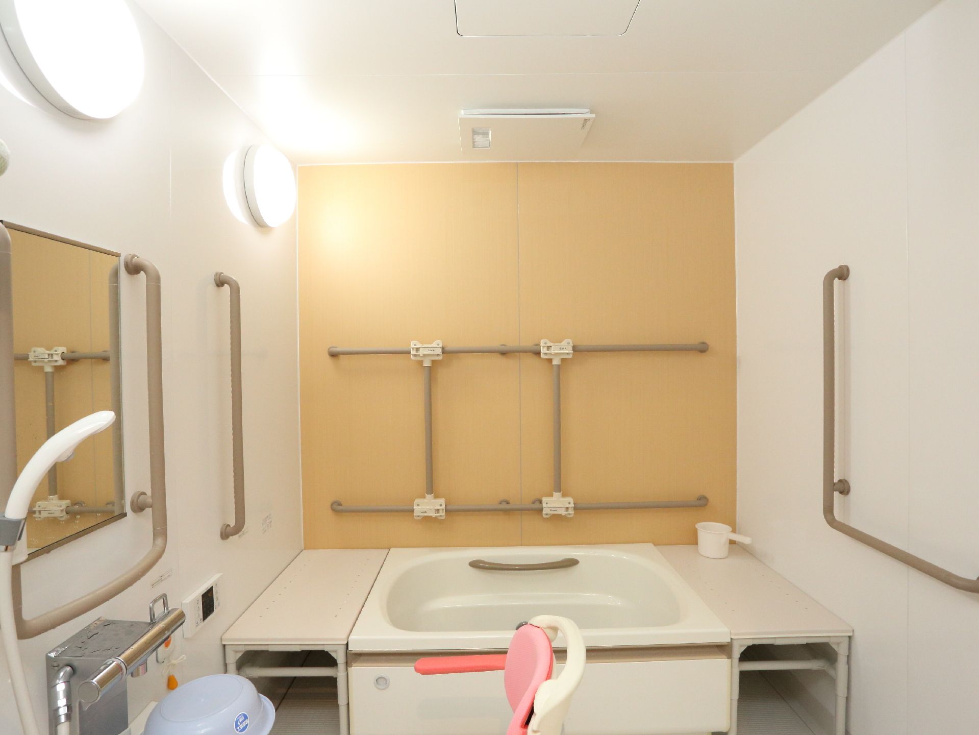 広めの浴室には壁全体に手すりが設置されている。シャワーの近くに緊急用の呼出ボタンがある。浴室用の椅子も置かれている。