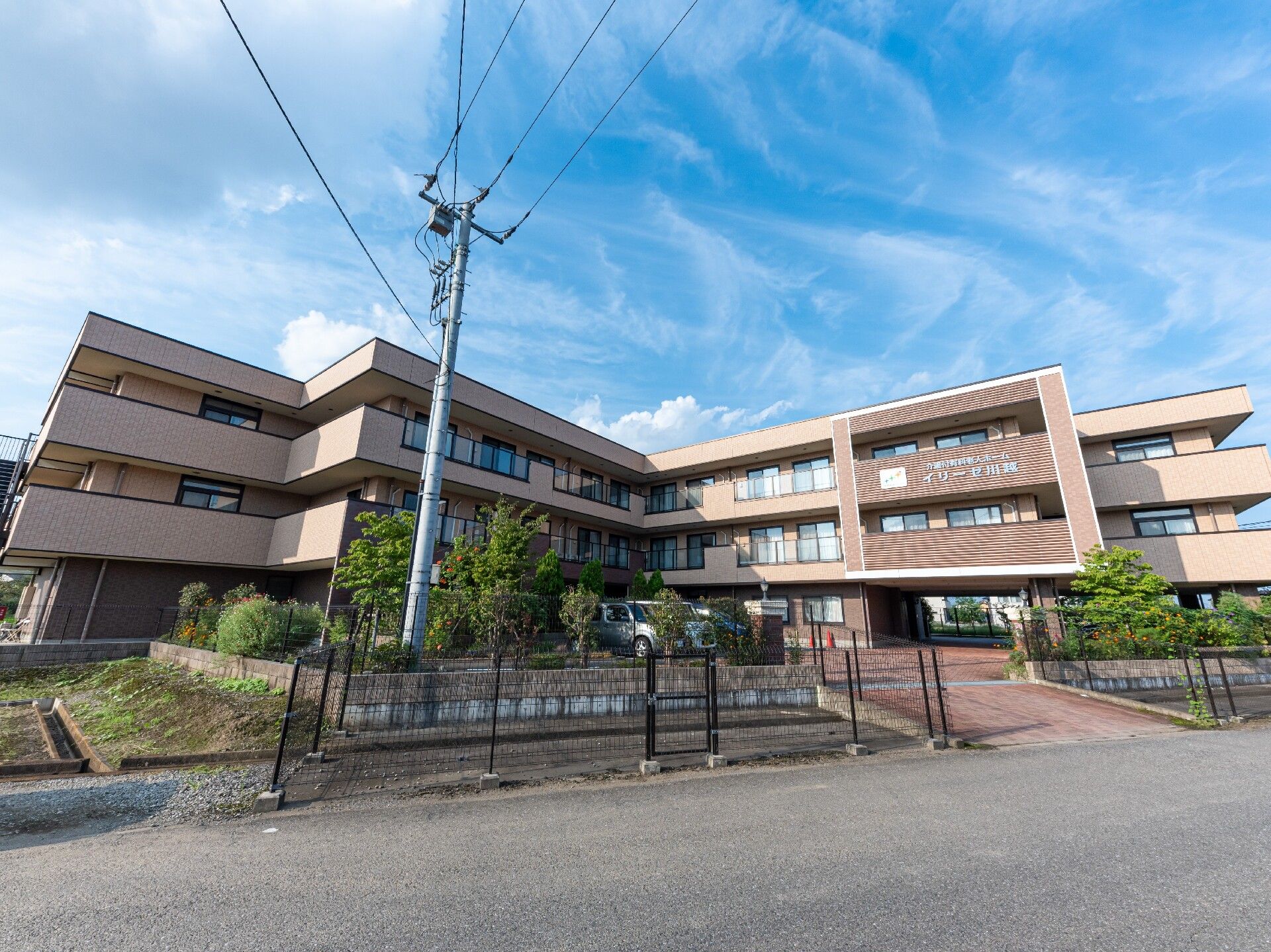 ブラウンが基調の外壁で3階建ての建物になっている。駐車場が広く、車で来訪する際に便利である。玄関前に車を一時停車できる。