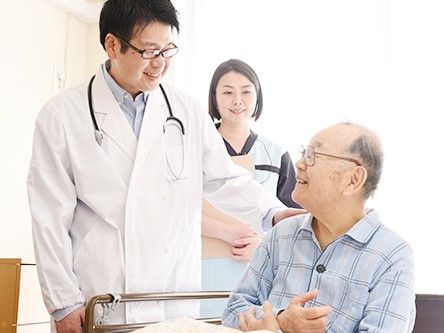 施設内を案内する男性スタッフと、男性に手を引かれながら歩くご年配の女性