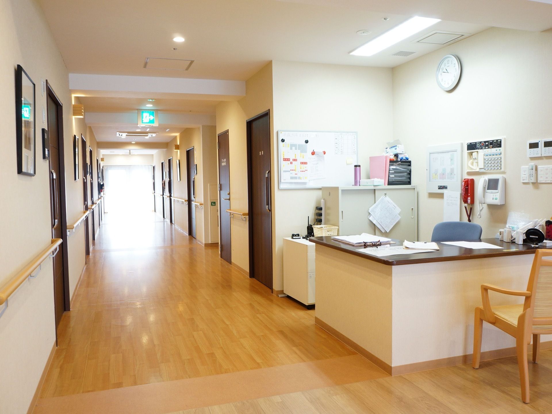 広々とした廊下の左右に居室が並んでおり、手すりが壁に設置されている。一角には、スタッフステーションが設けられている。