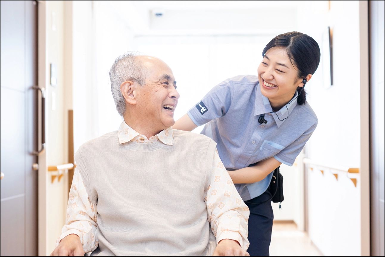 ベッドに腰かけたご年配の男性とにこやかに話す子連れの家族