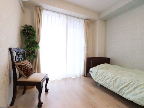 大きな窓があり、室内は明るく広い。壁側に木製のベッドがあり、反対がの壁に一人用の椅子が置かれている。