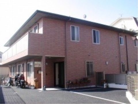 外壁は薄いベージュ系。正面方向は、各階に縦長の窓がいくつかある。施設名が入口の上部に赤地に白で大きく書かれている。