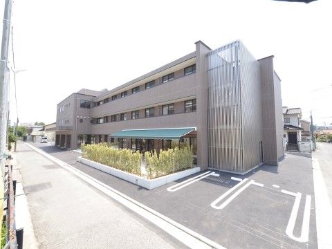 日よけの緑色のタープを設けたマンションの様な施設外観