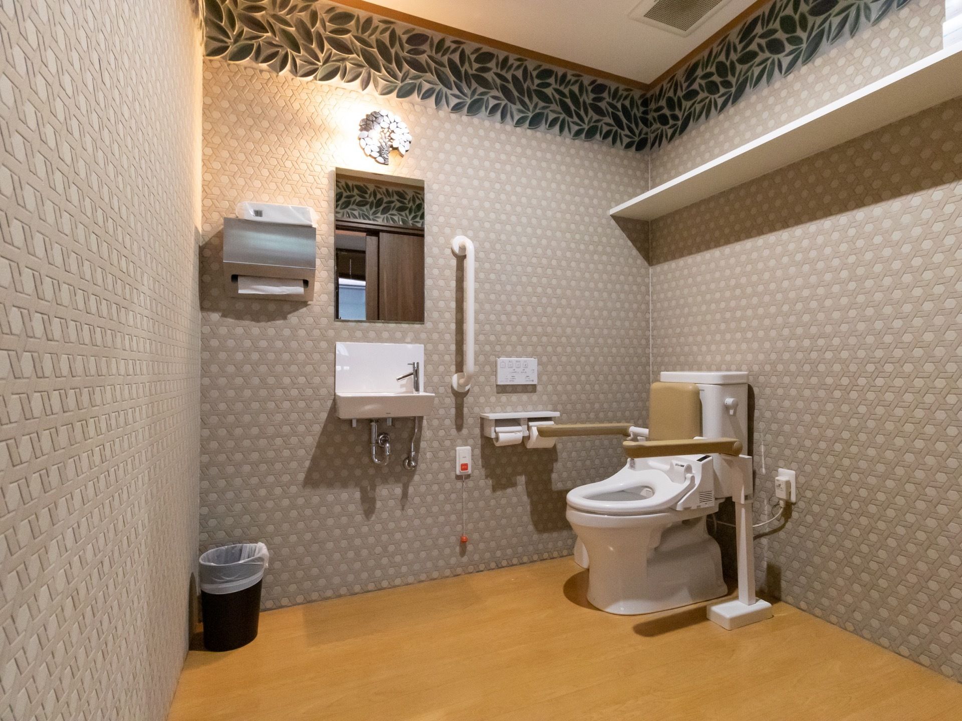 凹凸のあるグレーの壁紙を採用している。天井近くの壁面には、葉が並んだようなラインが入っている。個室内には、洗面台もある。