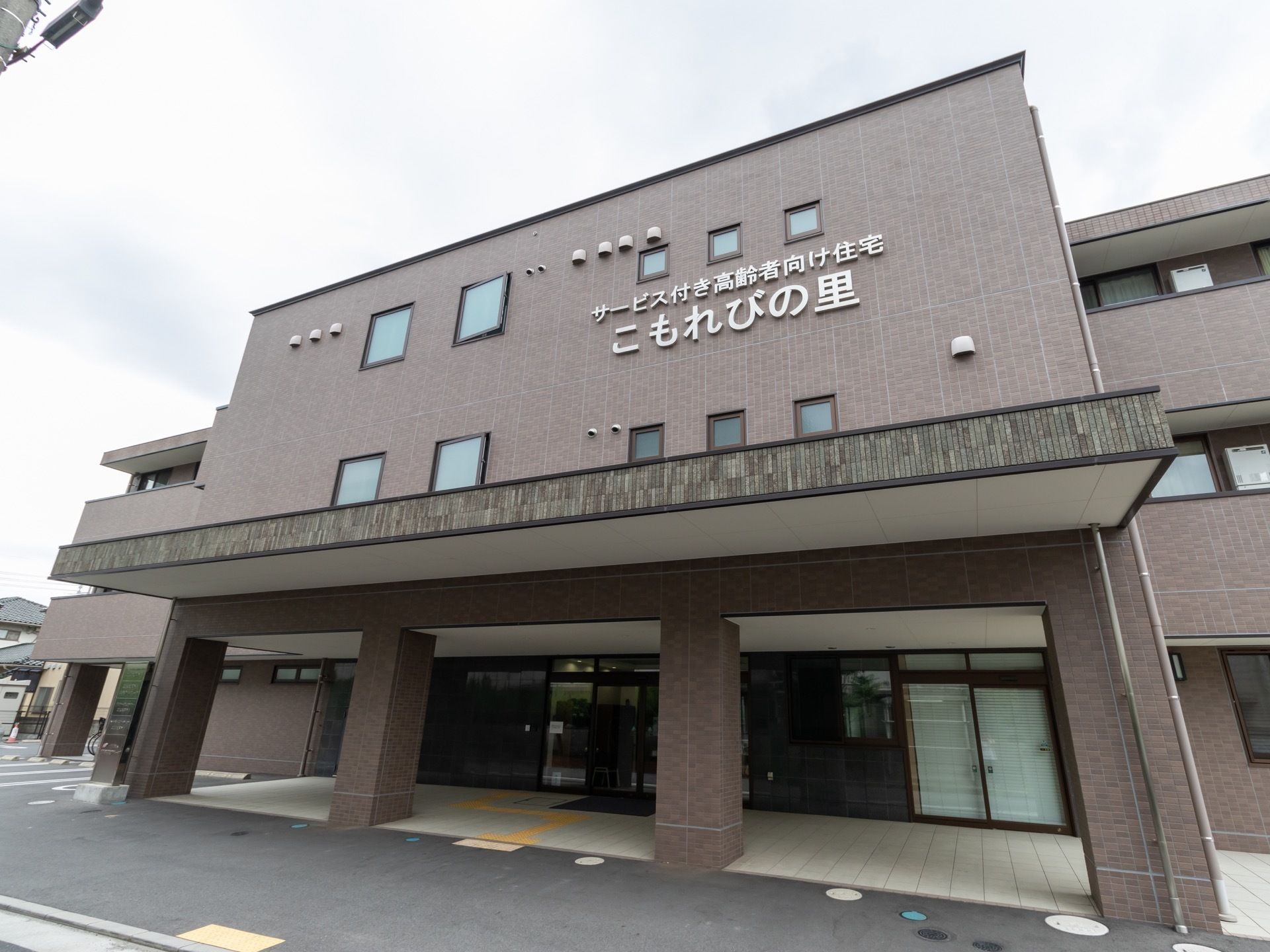 エントランス部分は大きな屋根があり、床は正方形のタイルが張ってある。ドアに向かって、黄色い点字ブロックが並んでいる。