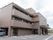 外壁が茶色の３階建の建物である。玄関前にはひさしが設けられている。２、３階部分にはベランダを完備している。