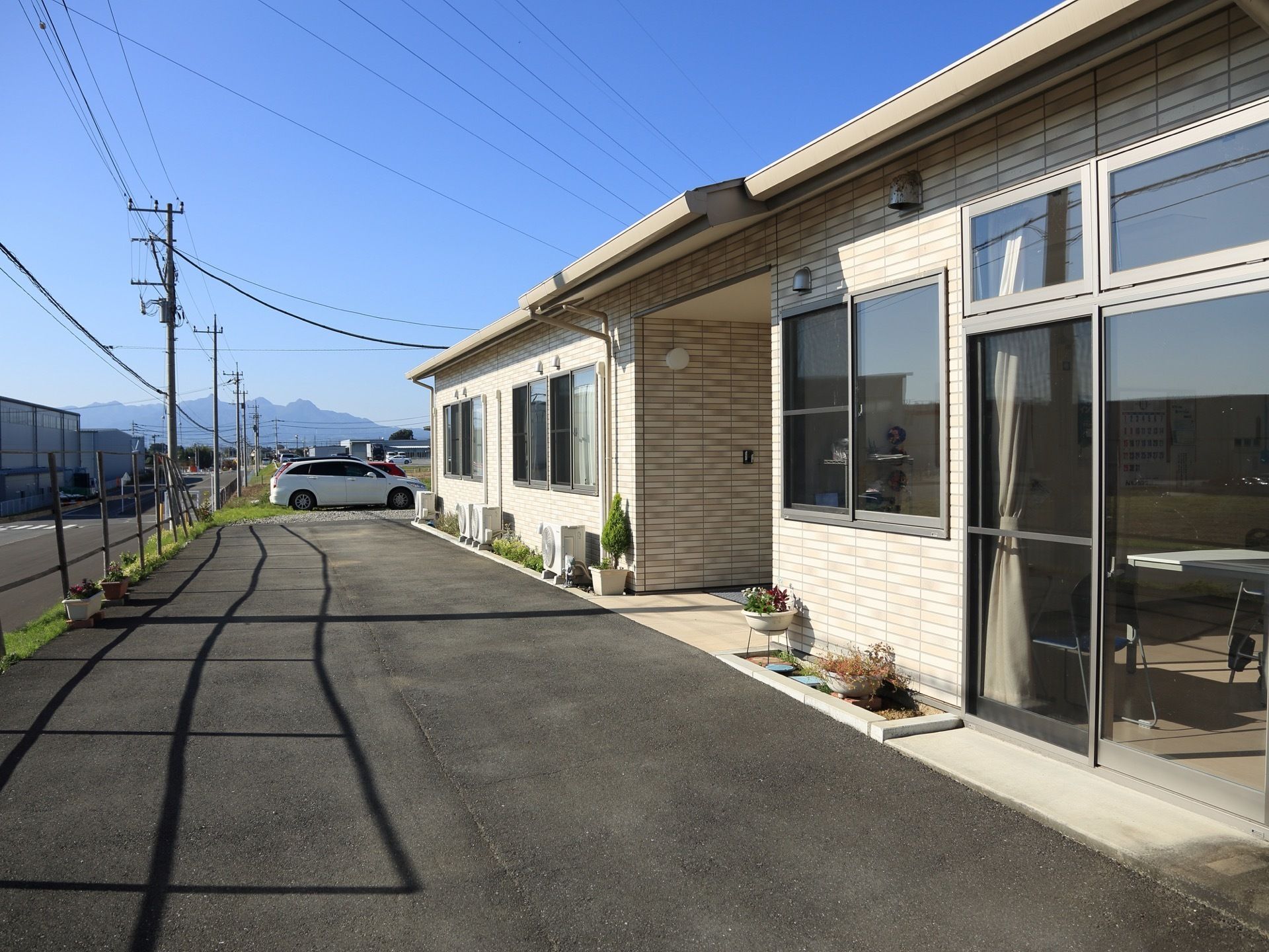 施設の周辺には大きな建物がなく隣接もしていない。車を停めるスペースがある。遠くには山が見え景色がいい。