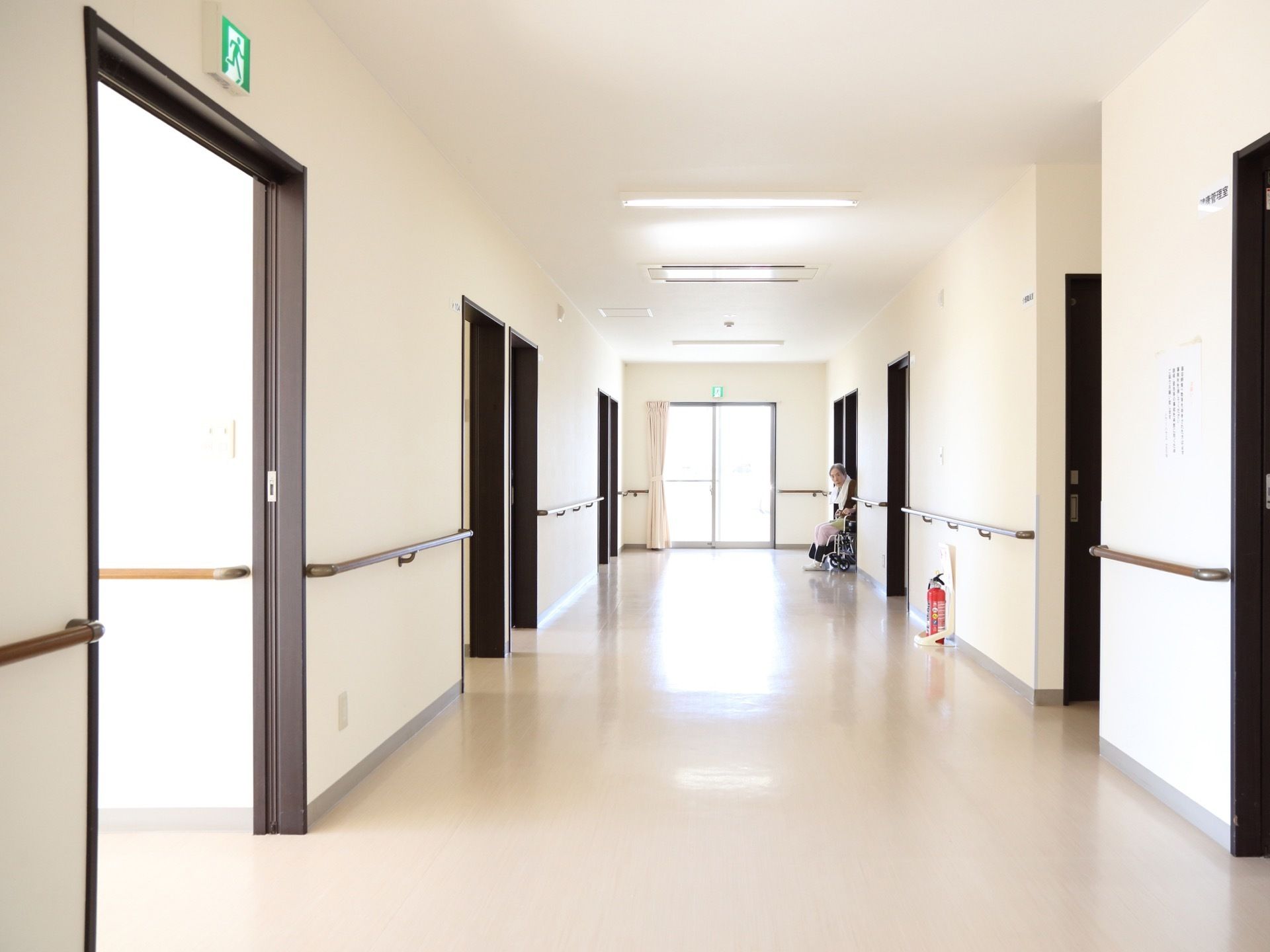 床と壁はベージュ系で扉と手すりはブラウン系になっている。非常口の案内がいくつも設置され、廊下には消火器が用意されている。