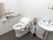 フラットなフロアに並んで設置されているトイレと洗面台。間にはトイレ寄りに手すりがある。トイレ側の壁には手すりとナースコール。