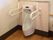 便器の周囲には白い手すりが設置されている。手をかざすと水洗するタイプのトイレである。ごみ箱が置かれている。床は木目調である。