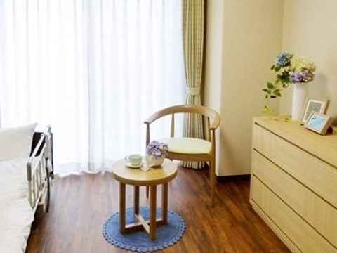 電動介護ベッドやチェスト、テーブルや椅子が置かれた居室