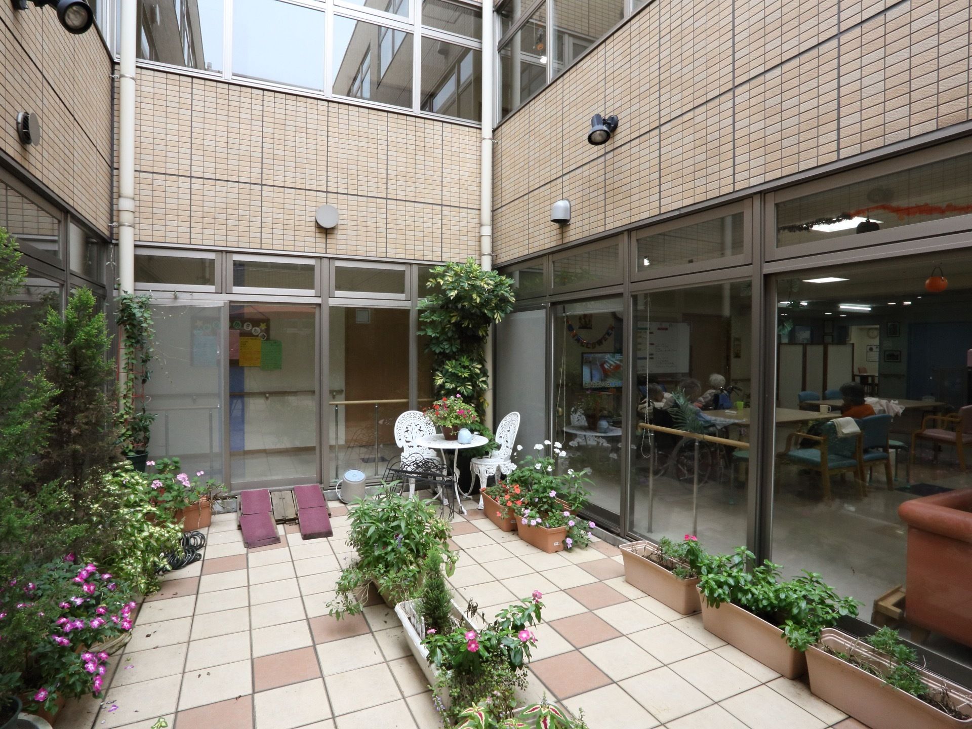 中庭にプランターが多く置かれ、植物がいっぱい咲いている。椅子とテーブルがあり、休憩することもできる。