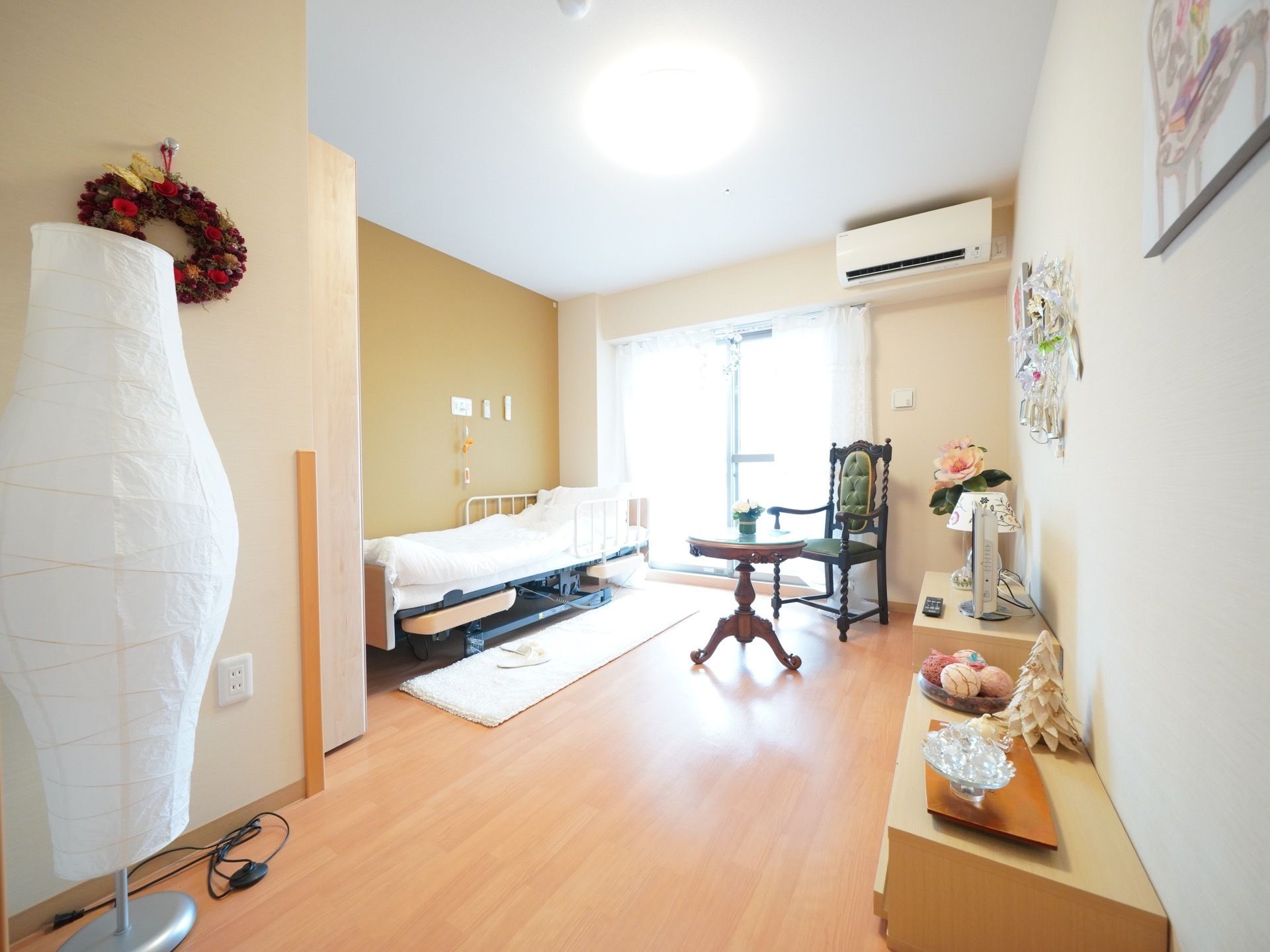 フローリング部屋に和の雰囲気がただようグリーンの壁が印象的である。アンティークなテーブルと椅子、照明スタンドもある。