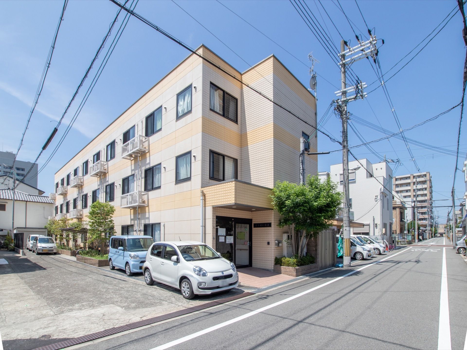 道路に面した3階建ての建物があり、施設の周囲にさまざまな樹木が植えられている。施設の隣に駐車スペースが用意されている。