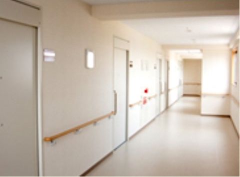 廊下にはゆったりとした空間が確保されている。ドアとドアの間がとても広く、居室の広さが伺える。白い壁に対し手すりは明るいベージュでよく目立つ。