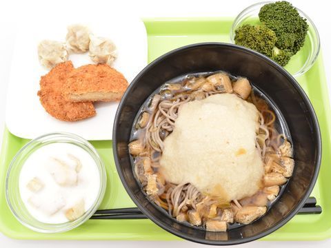 緑色のプレートに食事がのっている。とろろと油揚げのそば、茹でたブロッコリー、コロッケにしゅうまい、ヨーグルトサラダが用意されている。
