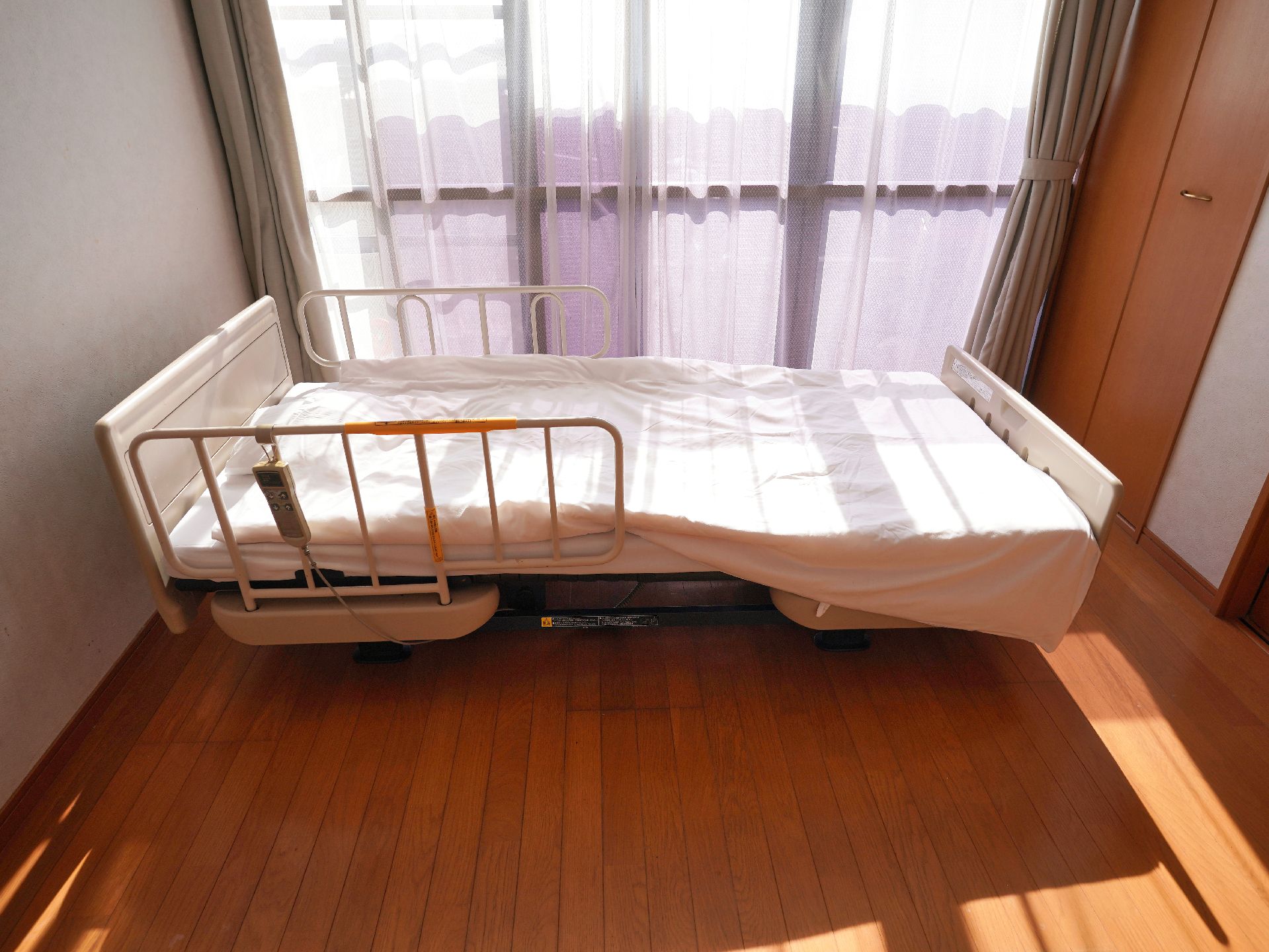 窓から日差しが入り、家具や介護ベッドが置かれている居室