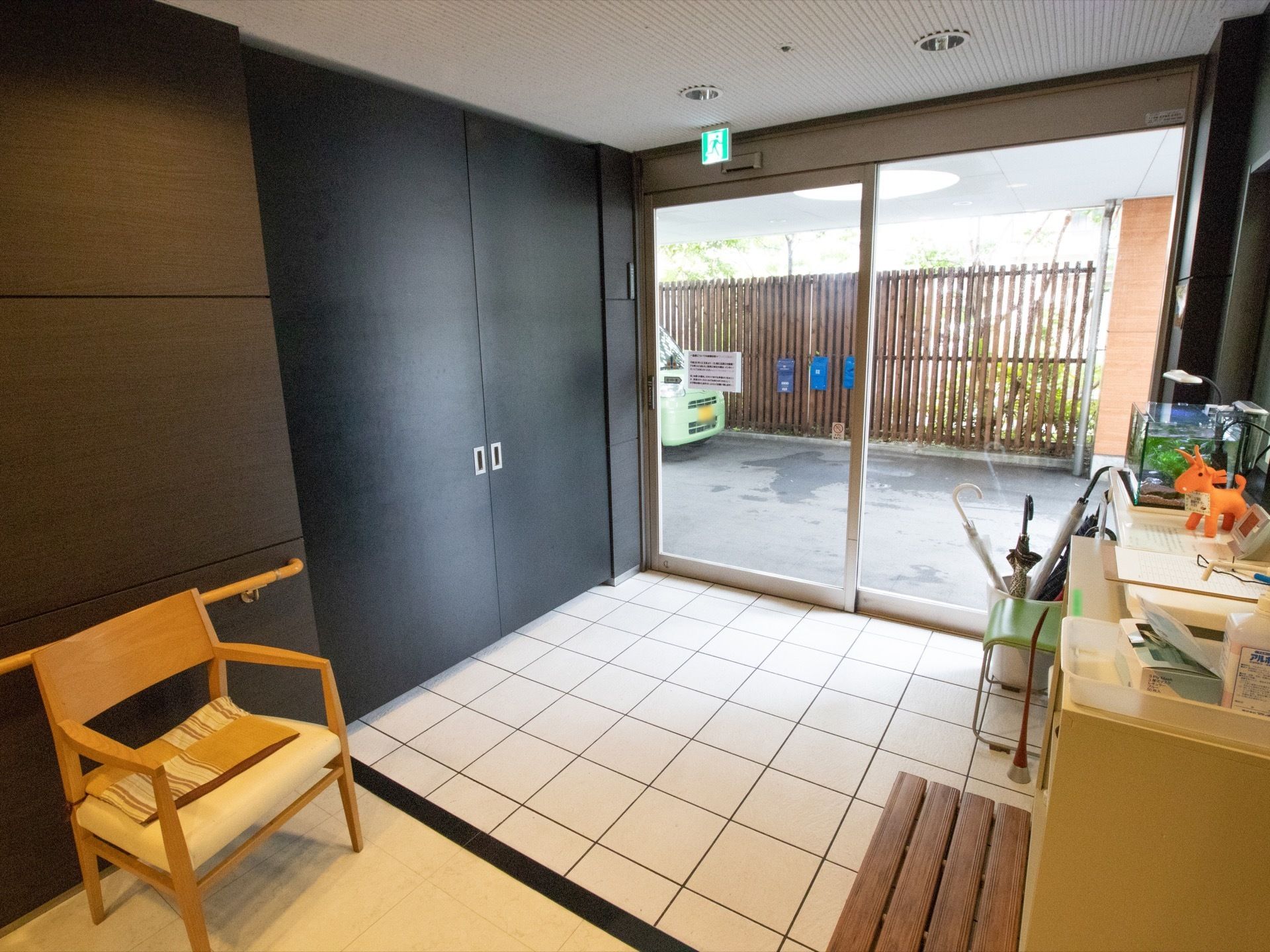 広い玄関は段差がなくフラットな作りとなっている。椅子が2つ置かれており、棚の上には水槽が設置されている。