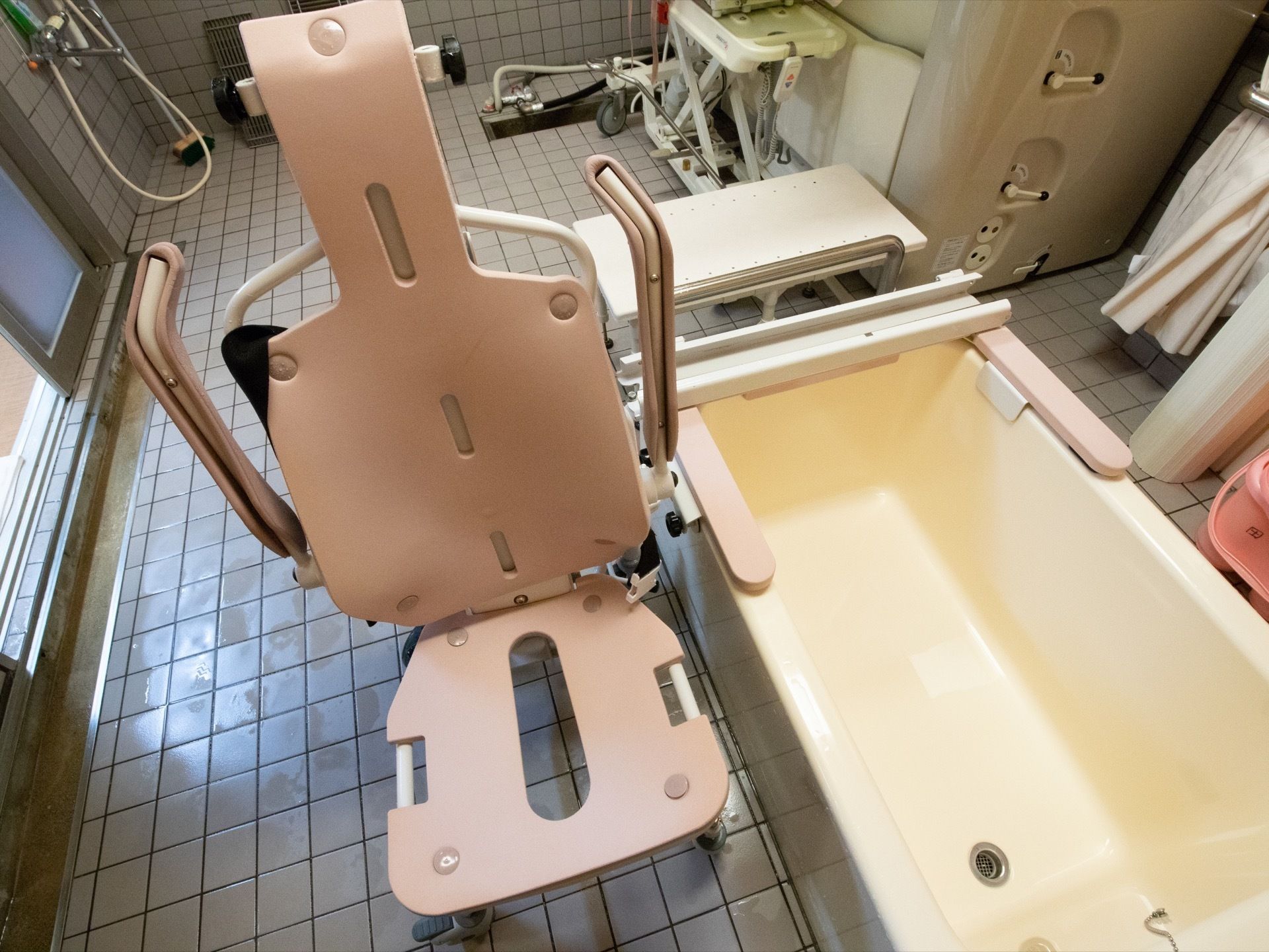 座ったまま入浴することが出来る介護浴槽が備えつけられた浴室。床と壁はグレーのタイル貼りになっている。