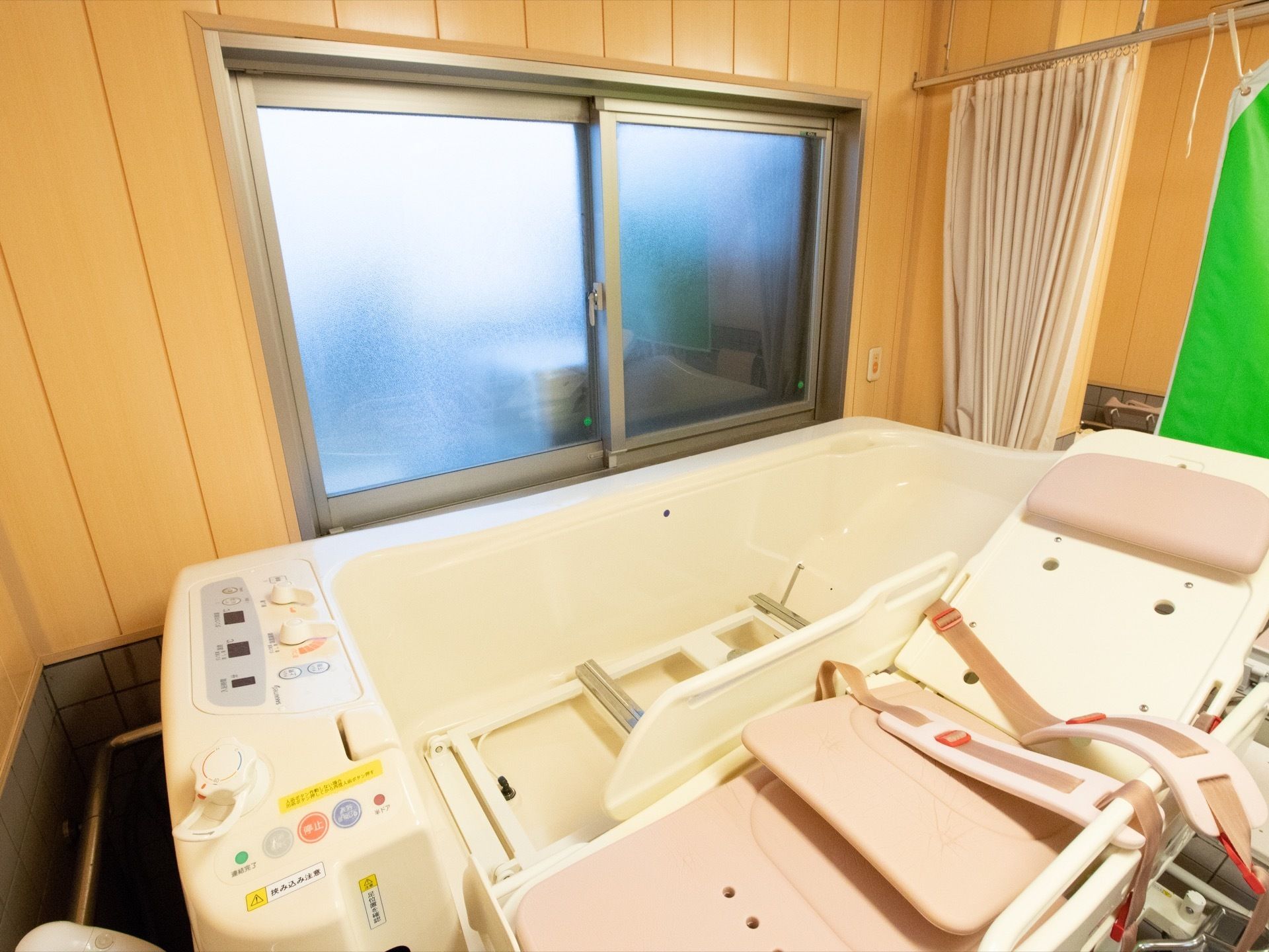 横になったまま入浴が可能な介護浴槽が備えつけられている浴室。壁には緊急時のための呼び出しボタンが設置されている。