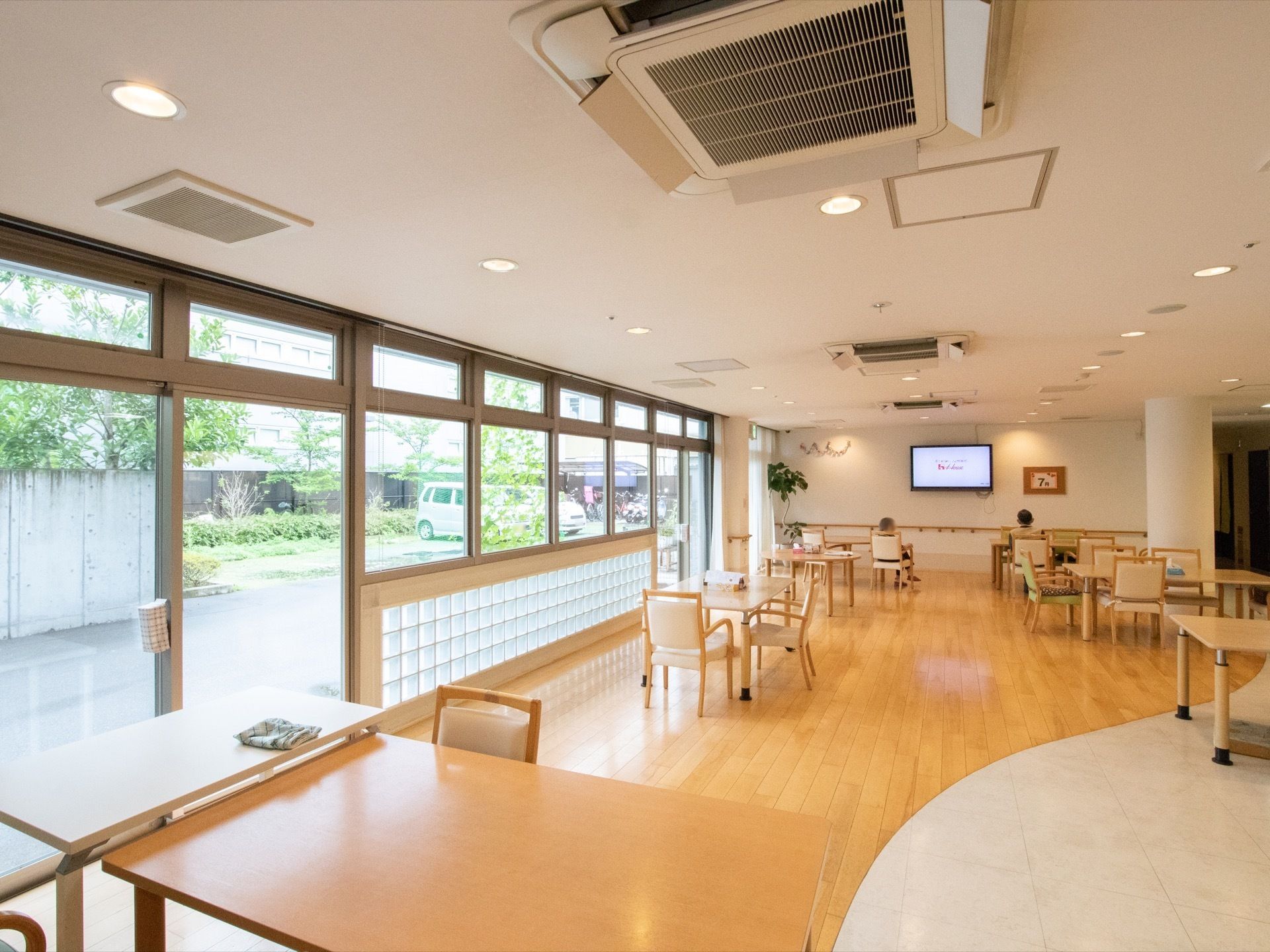 広々とした食堂は、窓が大きく取られ開放的な空間となっている。壁には大型のテレビと手すりが取りつけられている。