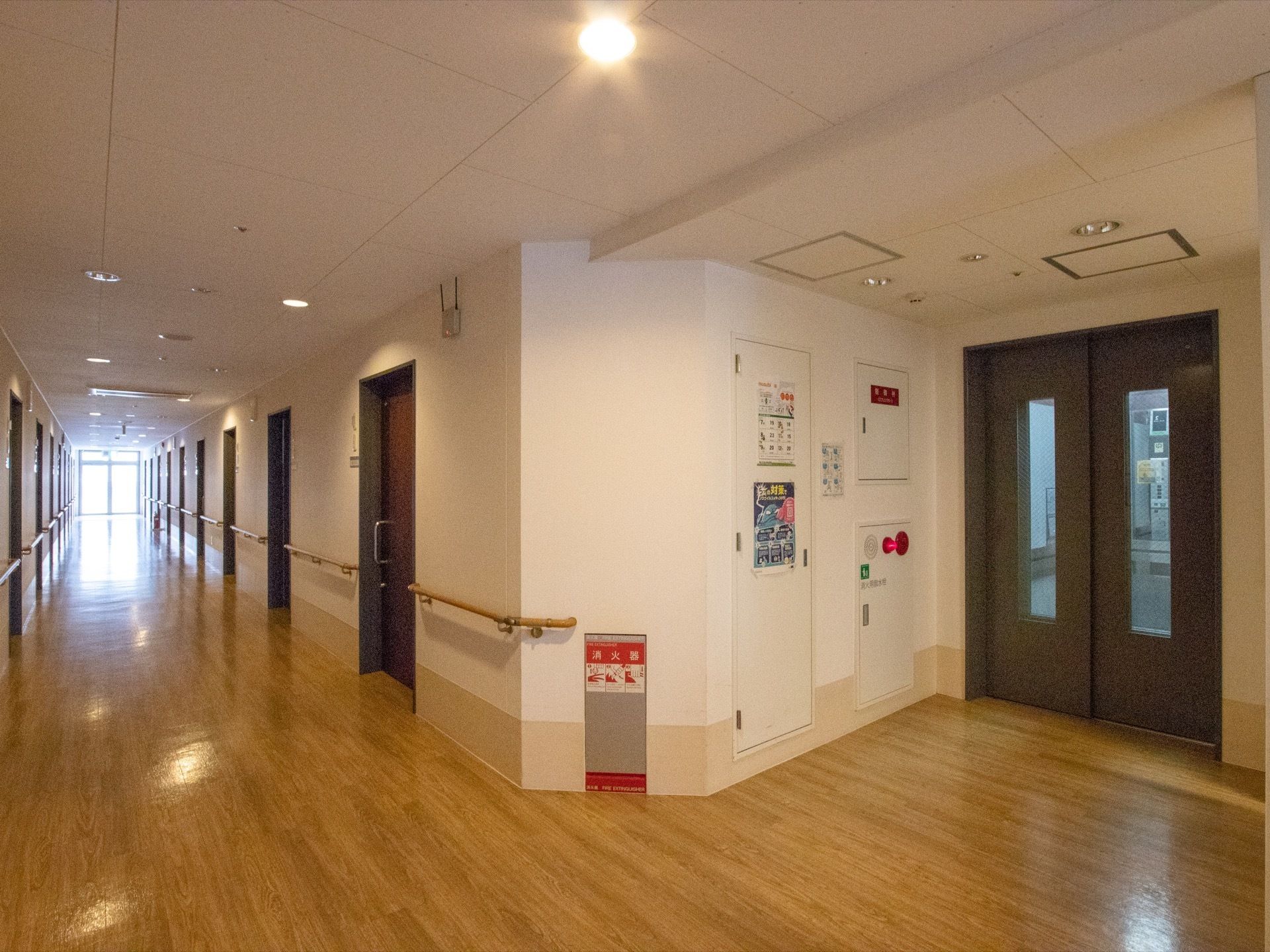 エレベーターや居室の扉は落ち着いたブラウンで統一されている。広い通路には手すりが備えつけられており、足腰が弱い入居者様も楽に移動ができる。