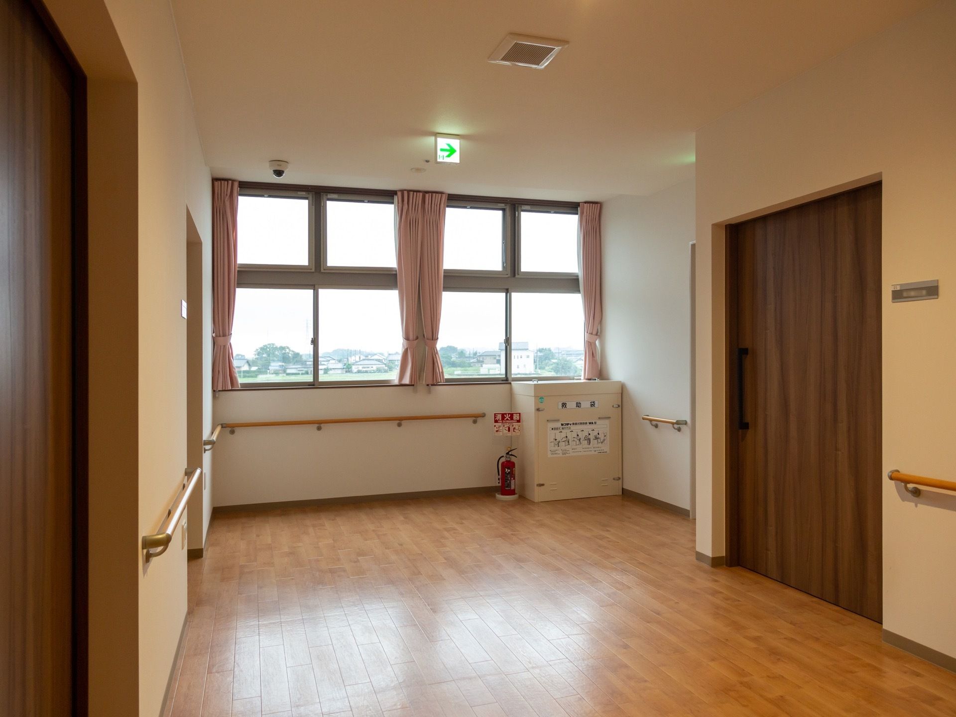 通路の突き当りに広々とした窓が設置されており、外の風景が眺められる。ピンク色のカーテンが備えつけられている。